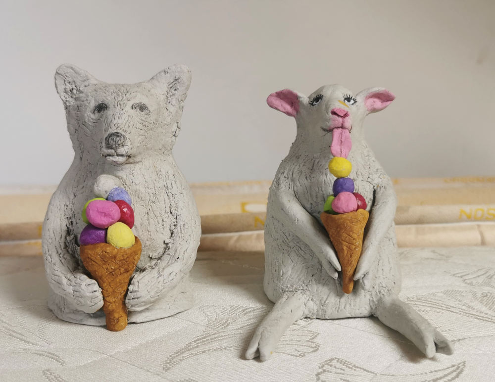two idio slimaks sitting eating ice cream from paper mache - but they are lamb and polar bear